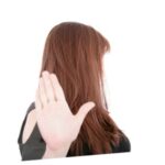 A woman holding up her hand and turning away as if asking someone to stop. Saying No with a hand gesture.