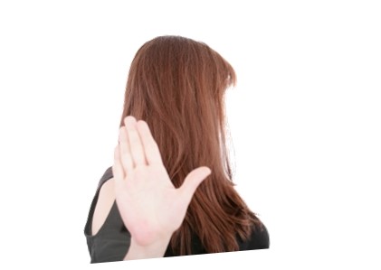 A woman holding up her hand and turning away as if asking someone to stop. Saying No with a hand gesture.